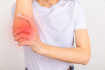 Young girl holding her elbow joint over white background. Pain and inflammation in the elbow.