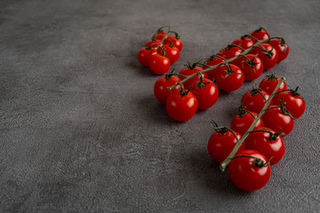 Cherry tomatoes on the vine on black stone background. Concept for healthy nutrition. Symbolic...