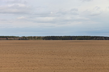 Beautiful vast brown ploughed field landscape against a blue sky on a spring day — land...