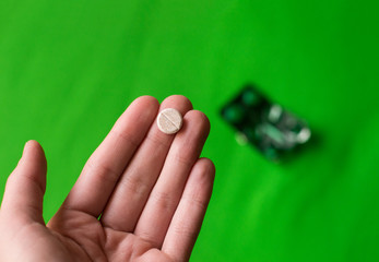 photo open green pack of pills on a green background and a tablet in hand