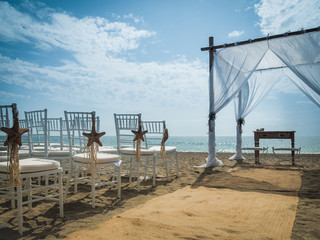 Romantic white beach wedding celebration with gazebo arch and chairs with starfish as decoration 