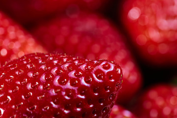 Imagen macro de una apetitosa fresa madura con detalle en sus semillas en un bol con otras fresas...