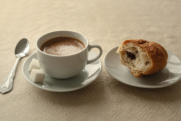 A Cup of coffee and a bit of kurasan on a plate . Breakfast