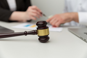 Legal support concept. People sitting at the desk with wooden hammer on it