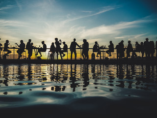 silhouette of people at a after work pool party in the sunset with light reflecting in the blue water pool