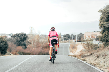 Fototapeta premium Back view of female cyclist cycling to the village