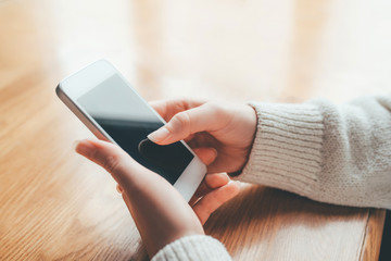 Women's hands use a smartphone for online shopping, social networking, or remote work. Close up image.