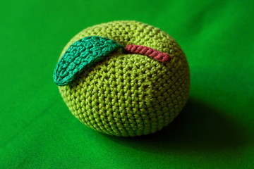photo knitted toy apple on a green background