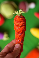 photo knitted toy carrot in hand on a green background
