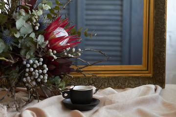 Cup of coffee and exotic bouquet stands on table with beige linen tablecloth on old frame background, holiday morning concept, selective focus