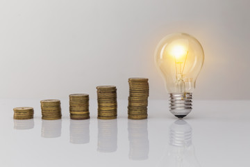 Hand holding a light bulb with coins stack. Creative ideas for saving money concept. Money management for the future.