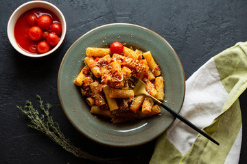 Tasty appetizing classic Italian pasta with tomato sauce, parmesan cheese and noodles on a plate on a dark table.Top view, horizontal.Italian pasta.Penne pasta in tomato sauce with chicken, tomatoes.