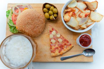 Piece of pizza Margherita, olives, burger and fries with beer on background on the wooden table. Fast food on old wooden background. Concept of junk eating. Top view - Image