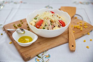 Bowl of Traditional Caesar Salad with Chicken and Bacon . Chicken Fillet and Parmesan Cheese . Peas. Corn kernels. olives on a small white bowl . Caesar salad on table - Healthy food style .