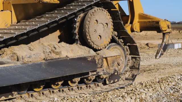 Bulldozer going backward, than forward, moving small amount of rubble or gravel at construction site.