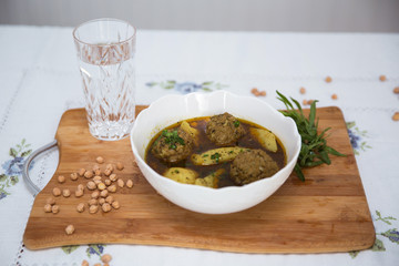 Traditional Azerbaijani Kufta bozbash - pea soup with lamb meatballs, made of minced meat and rice, zesty dried plum inside and boiled potatoes topped with dried mint and sumac . Kufta bozbash soup .