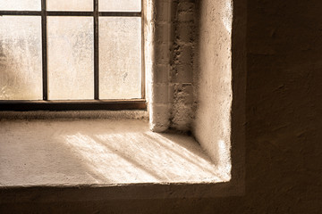 Corner of Old church window with beautiful glass structure throwing interesting shadows on the white window sill, 