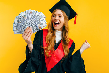 beautiful graduate girl, in a black gown, and a black master's hat, with dollars in her hands,...
