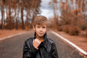 boy in a black jacket on an autumn alley