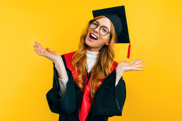 Happy graduate in a master's dress, on a yellow background. Concept of the graduation ceremony