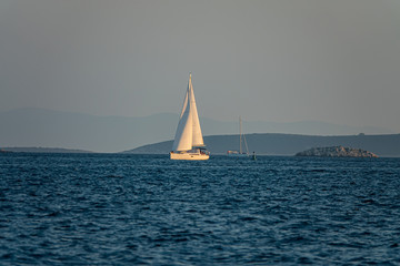 Fototapeta premium Sailing boat at sea. Yacht is sailing in the Adriatic Sea against the backdrop of forested islands, Croatia.