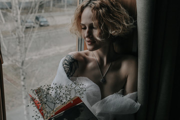 Obraz premium Beautiful young woman is sitting at the window with a book