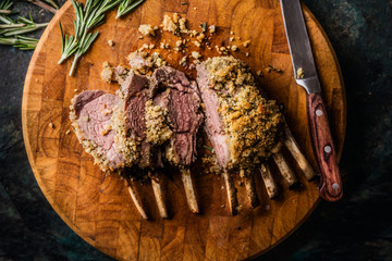 Close up of crusted lamb ribs cutlets with bone rar medium roasted on wooden cutting board with...