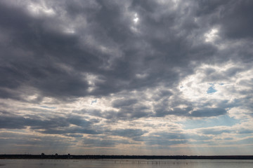 Cloudy dramatic sky with a narrow strip of horizon below. Creative vintage background.