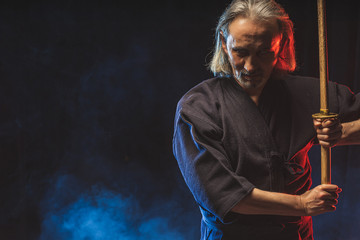 kendo combat warrior in traditional dress on smoky background, before competitions. man keen on traditional japanese martial art. Training, power.
