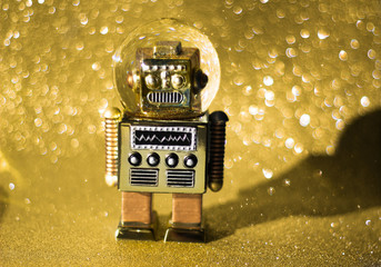 Vintage snowball toy robot on the glistening golden bokeh background. Retro toys minimal concept....
