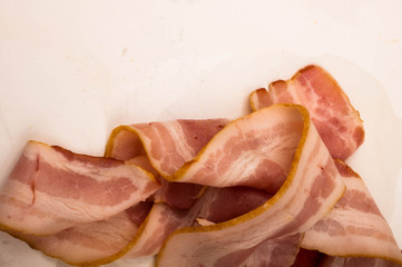 Slices of sausage and bacon on a white background. Close up.