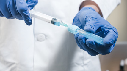 Doctor Drawing Vaccine Into Syringe in laboratory