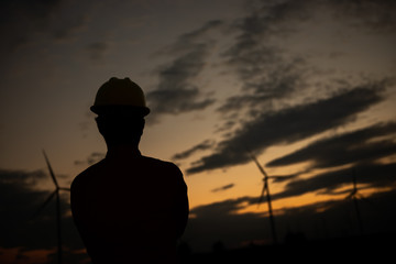 Silhouette of man engineer working and holding the report at wind turbine farm Power Generator Station on mountain,Thailand people