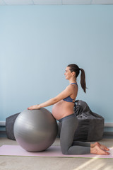 Pregnant caucasian woman on fitness with a ball. Yoga for expectant mothers. Girl in the classroom in preparation for childbirth. Pilates in the last trimester.