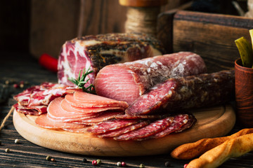 meat delicacies on wooden background, dried sausage on a cutting board