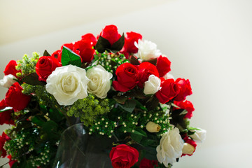Fresh white and red roses bouquet in a glass vase on a white background