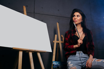 Blank Mock Up Canvas. The artist in a red plaid shirt with a brush in hands rejoices in the fact...