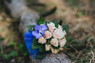 A wedding bouquet of fresh roses lies on a log in the forest on nature close-up. Photography, concept.