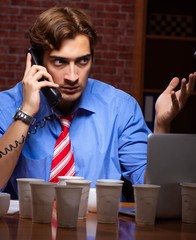 Young employee drinking coffee working at night shift
