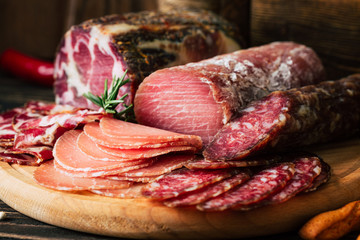 meat delicacies on wooden background, dried sausage on a cutting board