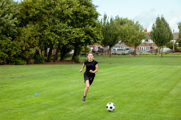 A teenage girl practicing and training in football in a local park