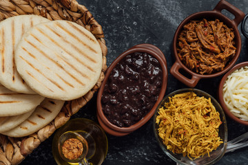 Top view of typical Latin American food. Group of arepas and different types of ingredients to fill them