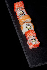 Philadelphia roll with salmon, cheese and cucumber on a black background. Sushi Philadelphia