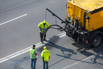 Road surface restoration work. The worker performs on road patcher work on the repair of cracks by...