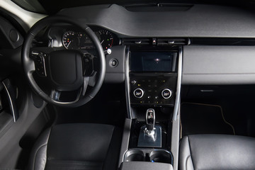 Interior of luxury suv car with black leather steering wheel and automatic shift gear.