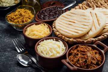Top view of typical Latin American food. Group of arepas and different types of ingredients to fill them