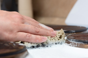 Woman is washing the surface of the electric stove with a cleaner close up.