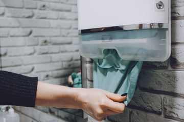 Coronavirus protection hand hygiene. Paper towels and alcohol gel antibacterial soap sanitizer in bathroom. Woman washes her hands and wipes with a paper towel