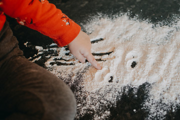 Flour Sensory Play for Toddlers. Easy flour sensory play activity for babies. Cute little girl sits on kitchen table and plays with flour - obrazy, fototapety, plakaty