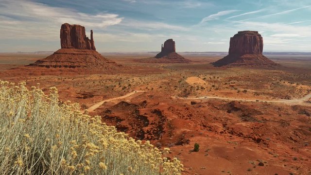 Monument Valley, United States. Red cliffs and red ground during bright sunny day. 4K